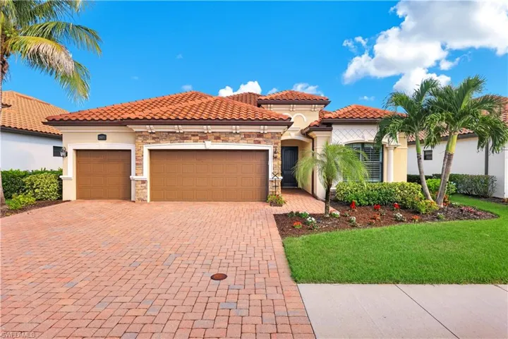 Single-story residence featuring a terracotta-tiled roof, stone veneer accents, multi-car garage, and brick-paver driveway