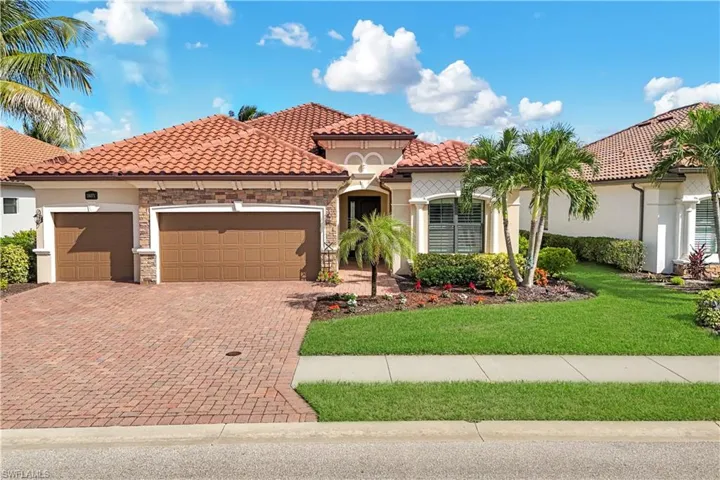 Exterior featuring a clay tile roof, stone masonry accents, a brick-paver driveway, and a three-car garage