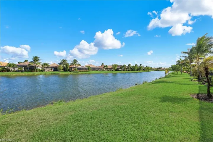 Waterfront parcel featuring a grass lawn and mature palm trees