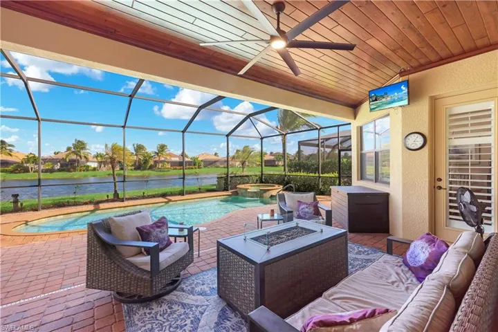 Screened-in lanai featuring a wood-plank ceiling, ceiling fan, brick paver flooring, custom pool with an integrated spa, and water frontage