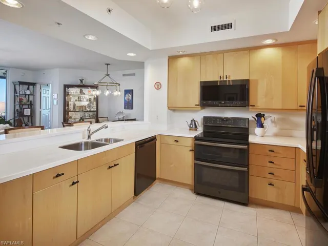 Kitchen with black appliances, kitchen peninsula, sink, and light brown cabinets