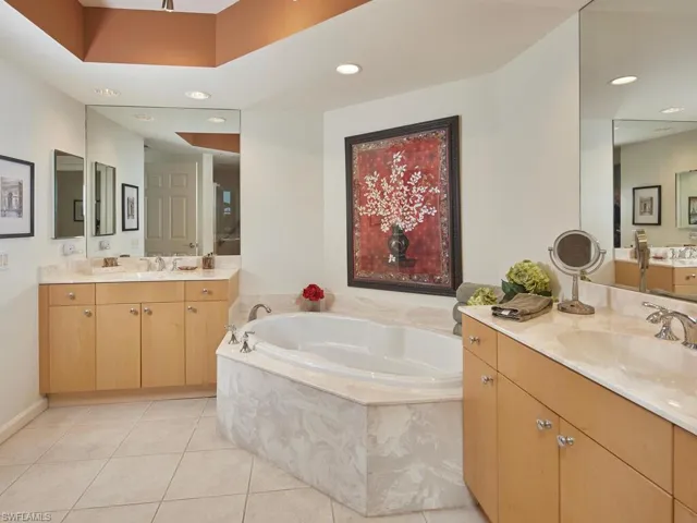 Bathroom with tile patterned flooring, tiled bath, and vanity