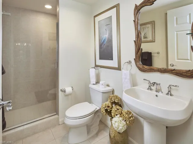 Bathroom featuring tile patterned flooring, toilet, sink, and an enclosed shower