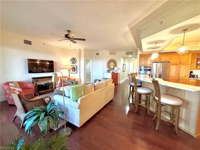 Living room with dark hardwood / wood-style flooring, ceiling fan, and crown molding