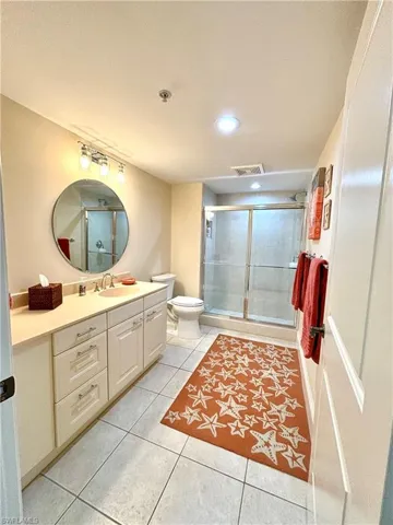 Bathroom with tile patterned flooring, vanity, a shower with shower door, and toilet