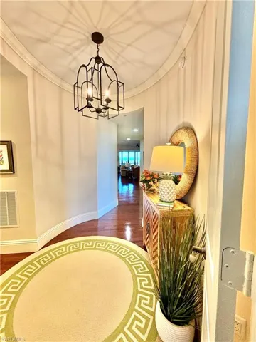 Hall with dark hardwood / wood-style flooring, an inviting chandelier, and crown molding