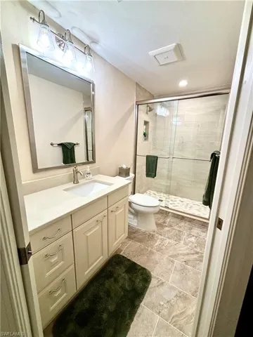 Bathroom with vanity, toilet, and a shower with shower door