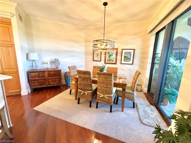 Dining area featuring a chandelier, crown molding, and dark wood-type flooring