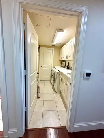 Clothes washing area with washer and clothes dryer, cabinets, and light hardwood / wood-style flooring