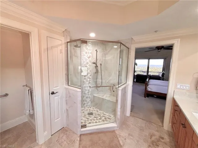Master Bathroom with a shower with door, crown molding, and ceiling fan