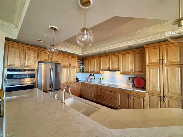Kitchen featuring  stainless appliances, crown molding, pendant lighting, and a tray ceiling