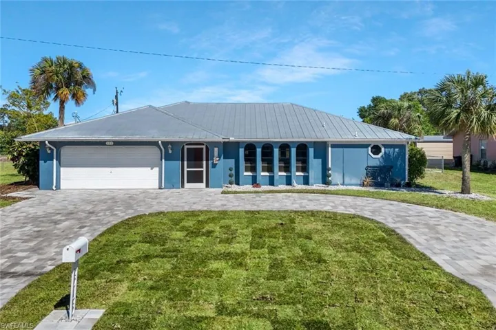 Single story home featuring a front lawn, decorative driveway, a garage, and stucco siding