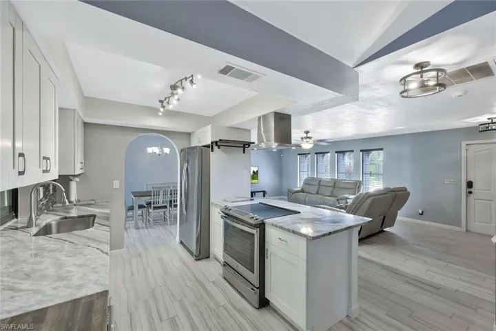 Kitchen with visible vents, island exhaust hood, a sink, open floor plan, and appliances with stainless steel finishes