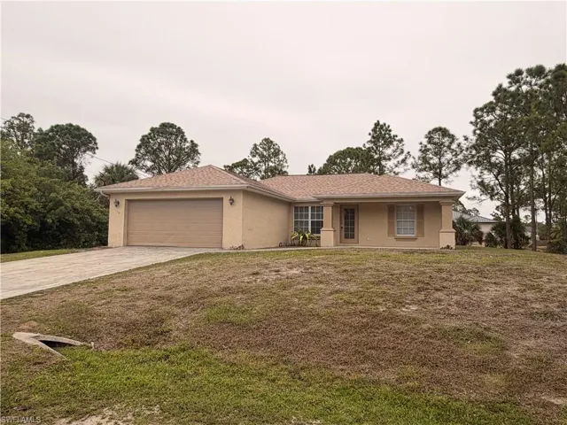 Ranch-style house with stucco siding, an attached garage, driveway, and a front yard