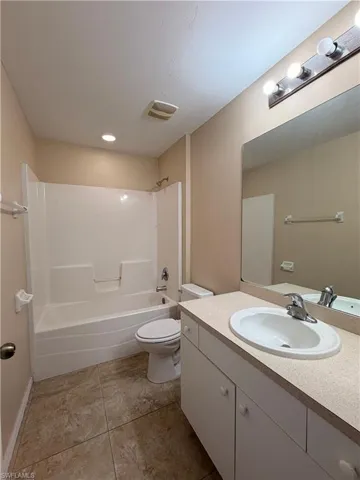 Bathroom with vanity, bathtub / shower combination, and light tile patterned floors