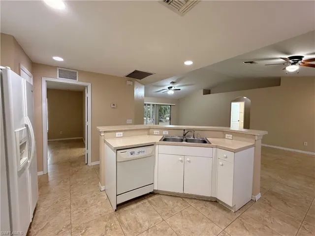 Kitchen featuring ceiling fan, a center island with sink, white appliances, open floor plan, and recessed lighting