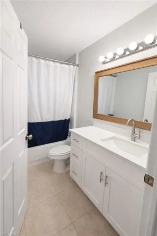 Bathroom with vanity, a textured ceiling, light tile patterned flooring, and shower / tub combo with curtain