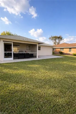 Back of house featuring a lawn, stucco siding, a patio area, and an outdoor lounge area