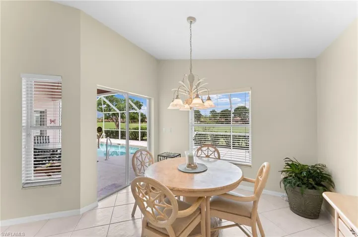 Dining space with a chandelier, light tile patterned floors, a healthy amount of sunlight, and vaulted ceiling
