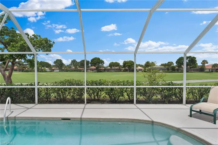View of swimming pool featuring glass enclosure and a patio area