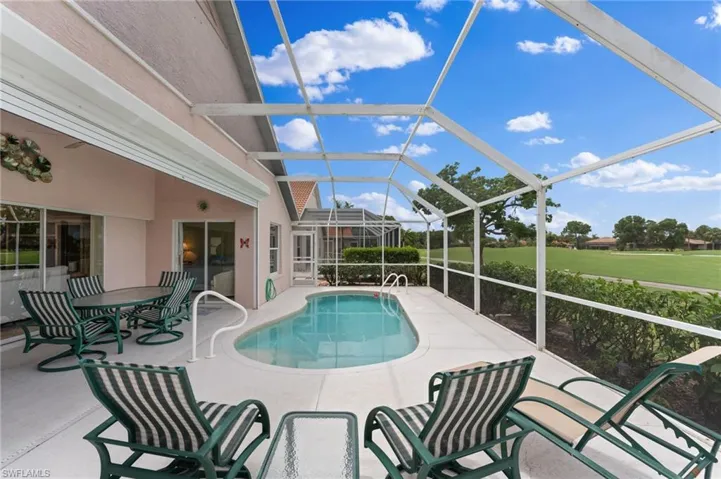 View of swimming pool with glass enclosure and a patio area