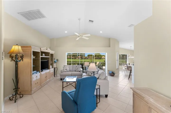 Tiled living room with ceiling fan and lofted ceiling
