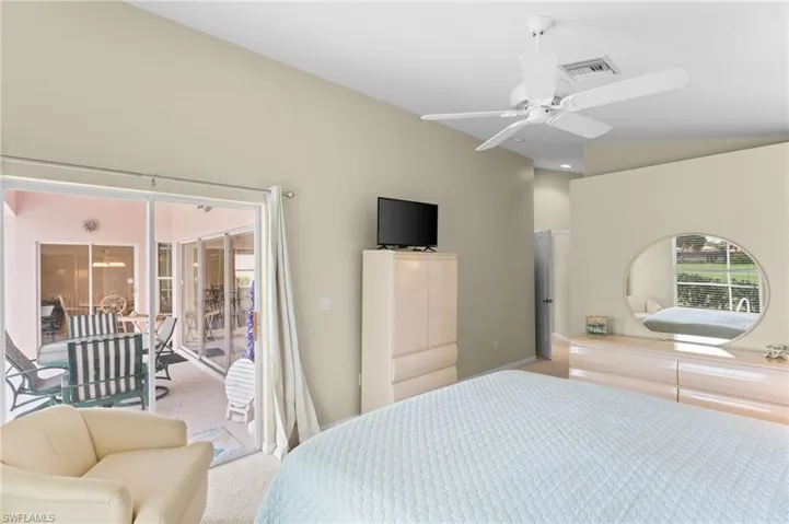 Bedroom with light colored carpet, vaulted ceiling, and ceiling fan