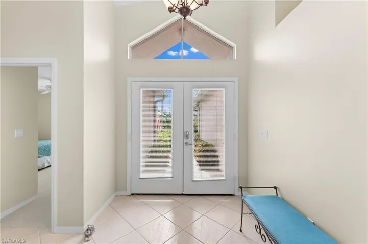 Entryway with a chandelier, light tile patterned floors, a towering ceiling, and french doors