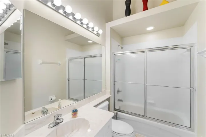 Full bathroom featuring vanity, toilet, and bath / shower combo with glass door