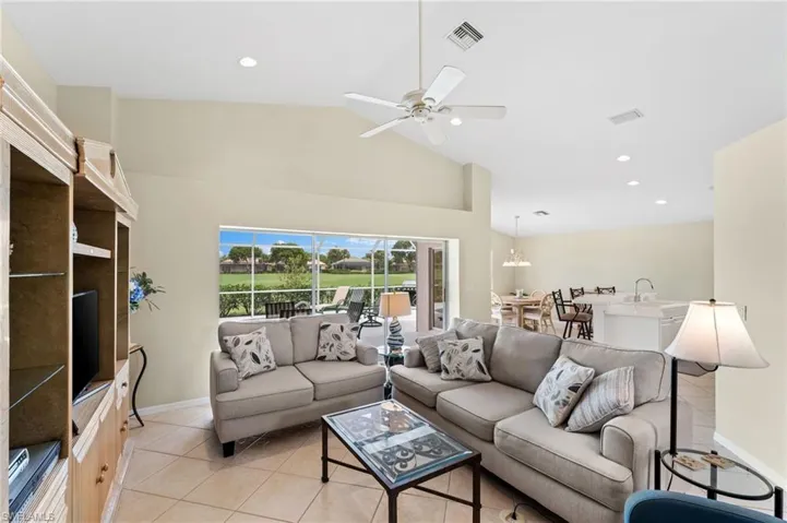 Living room with ceiling fan, light tile patterned floors, sink, and high vaulted ceiling