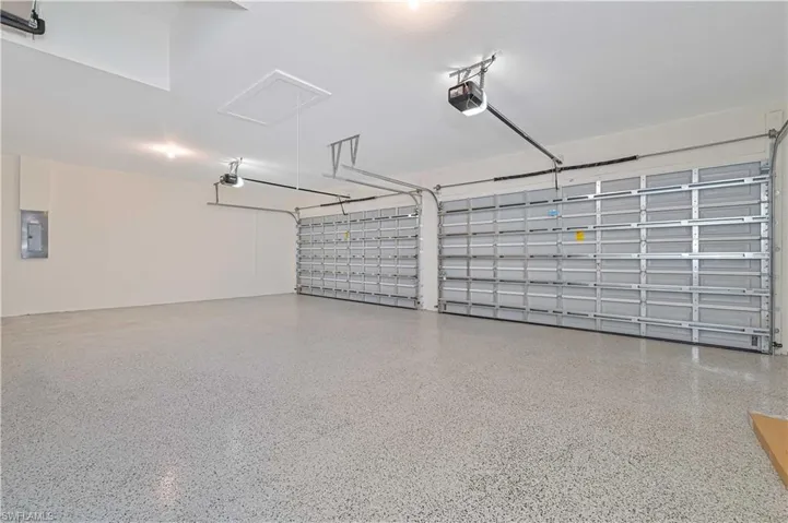 Spacious two-car garage featuring a speckled epoxy floor, two automatic garage door openers, and recessed lighting
