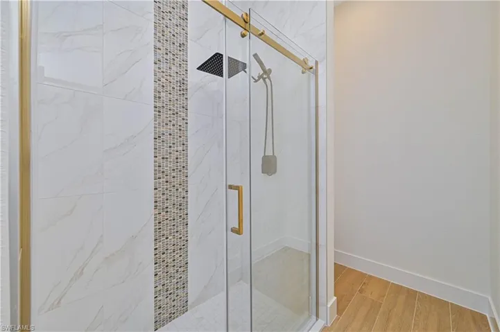 Walk-in shower featuring a gold-finish sliding glass door