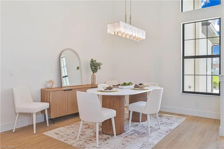 Dining area featuring high ceilings, wood-finish flooring, and a large grid-pattern window