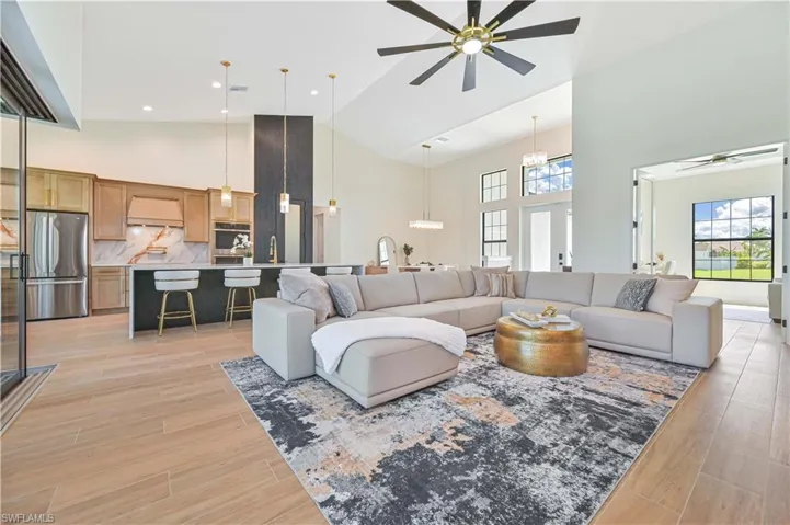Open-concept living space featuring wood-finish flooring, vaulted ceilings, and large windows
