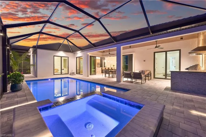 Screened outdoor living area featuring a rectangular pool and integrated spa