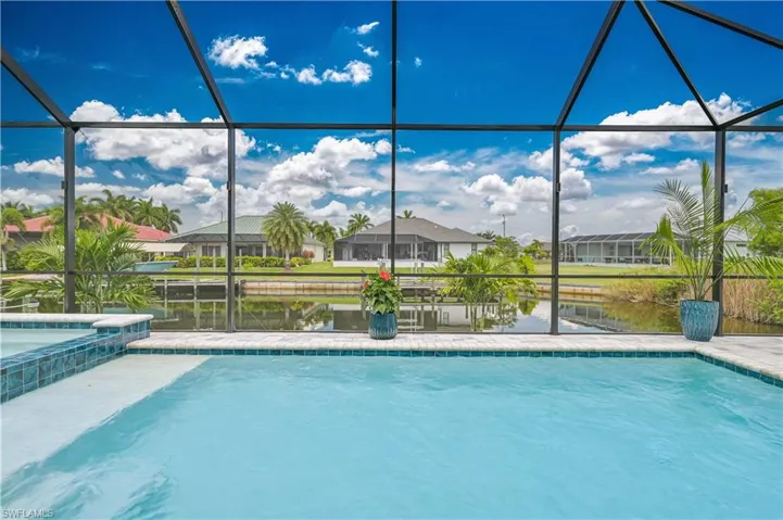 Screened-in outdoor living space featuring a swimming pool and integrated spa