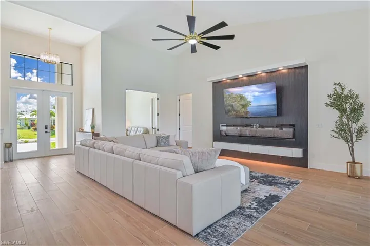 Spacious living area featuring high ceilings, wood-finish flooring, and an entertainment wall with integrated lighting