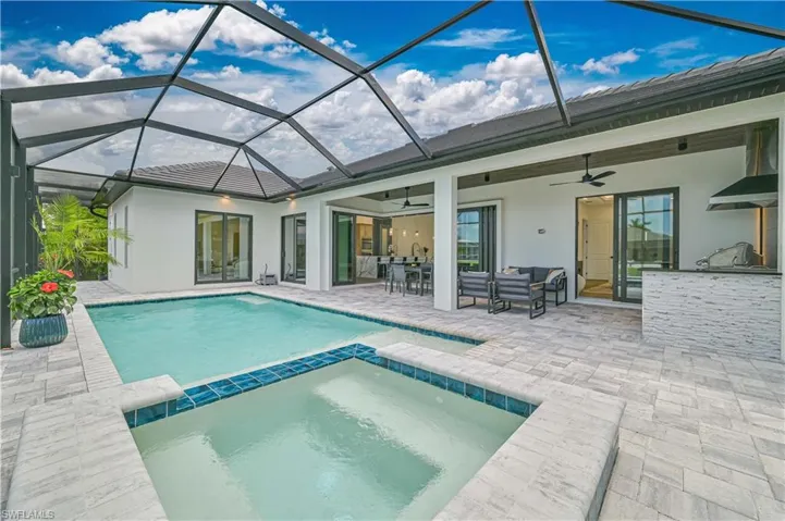 Screened lanai featuring a swimming pool and integrated spa with blue tile accents