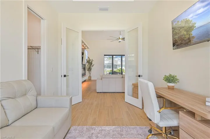 Double French doors with frosted glass panels open to a bright interior space with tile flooring