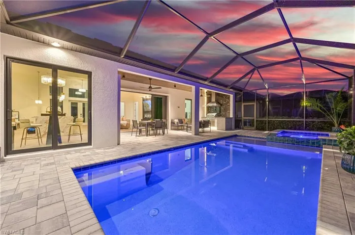 Screened outdoor living area featuring a rectangular pool and integrated spa