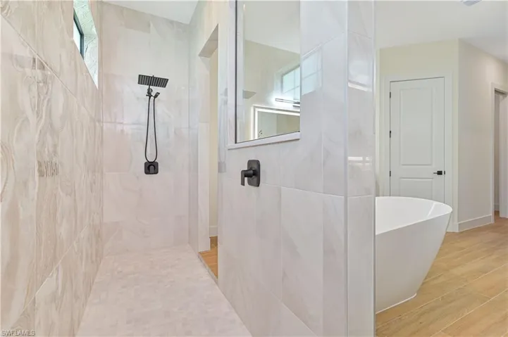 Spacious walk-in shower with large format tile walls and a mosaic tile floor