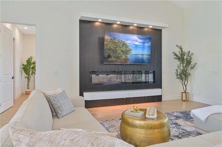 Living area featuring a textured accent wall with an integrated linear fireplace and display shelving
