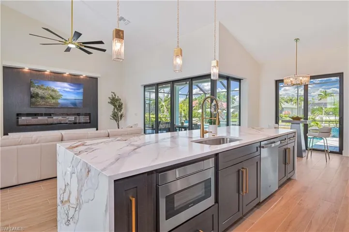 Gourmet kitchen island with waterfall-edge countertop, undermount sink, and integrated microwave drawer