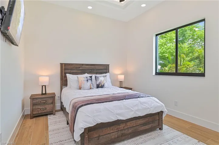 Vaulted ceiling bedroom featuring wood-finish flooring and recessed lighting
