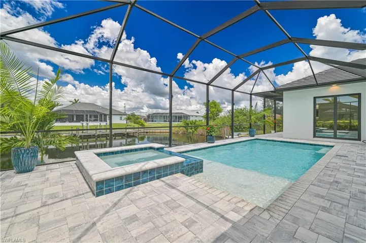 Screened lanai featuring a swimming pool, integrated spa, and paver decking