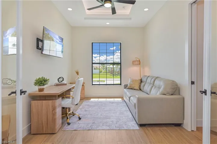 Dedicated room featuring wood-finish flooring, a large window, recessed lighting, and a tray ceiling with a ceiling fan