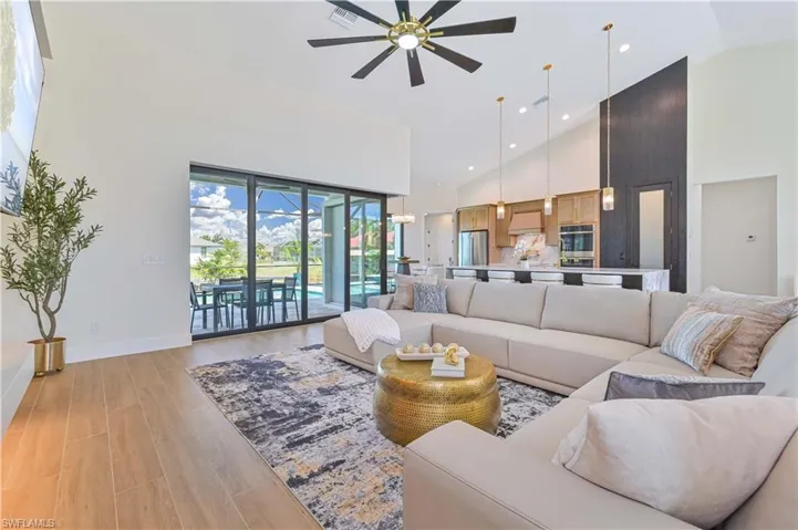 Spacious open-concept living area featuring wood-finish flooring, vaulted ceilings, and a large ceiling fan