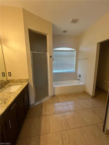 Full bath featuring a stall shower, a garden tub, and vanity
