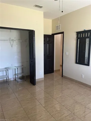 Bedroom featuring light marble finish flooring, baseboards, and a closet