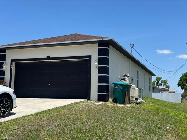 View of side of home with an attached garage, stucco siding, driveway, and roof with shingles
